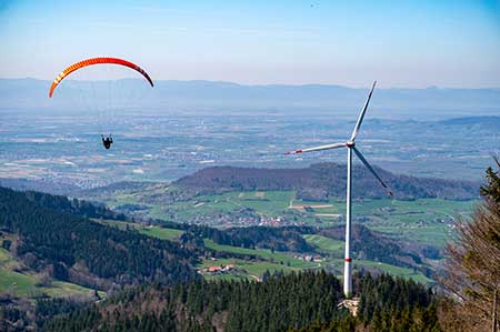 Windrad mit Blick in die Rheinebene und Paraglider