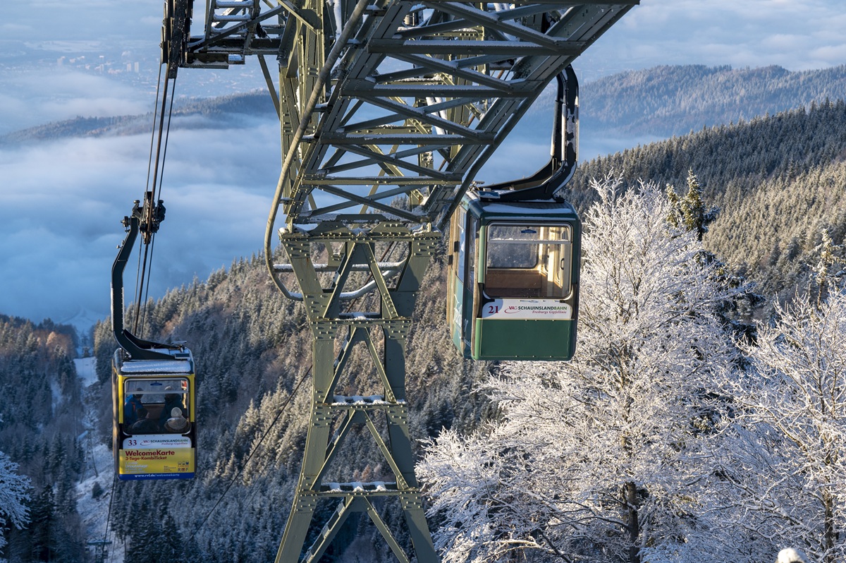 Zwei Gondeln der Schauinslandbahn fahren über frostige Berge.
