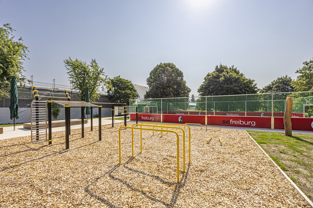 Die Sportfläche des Freibads Westbad, verschiedene Sportgeräte im Vordergrund, Fußballplatz im Hintergrund