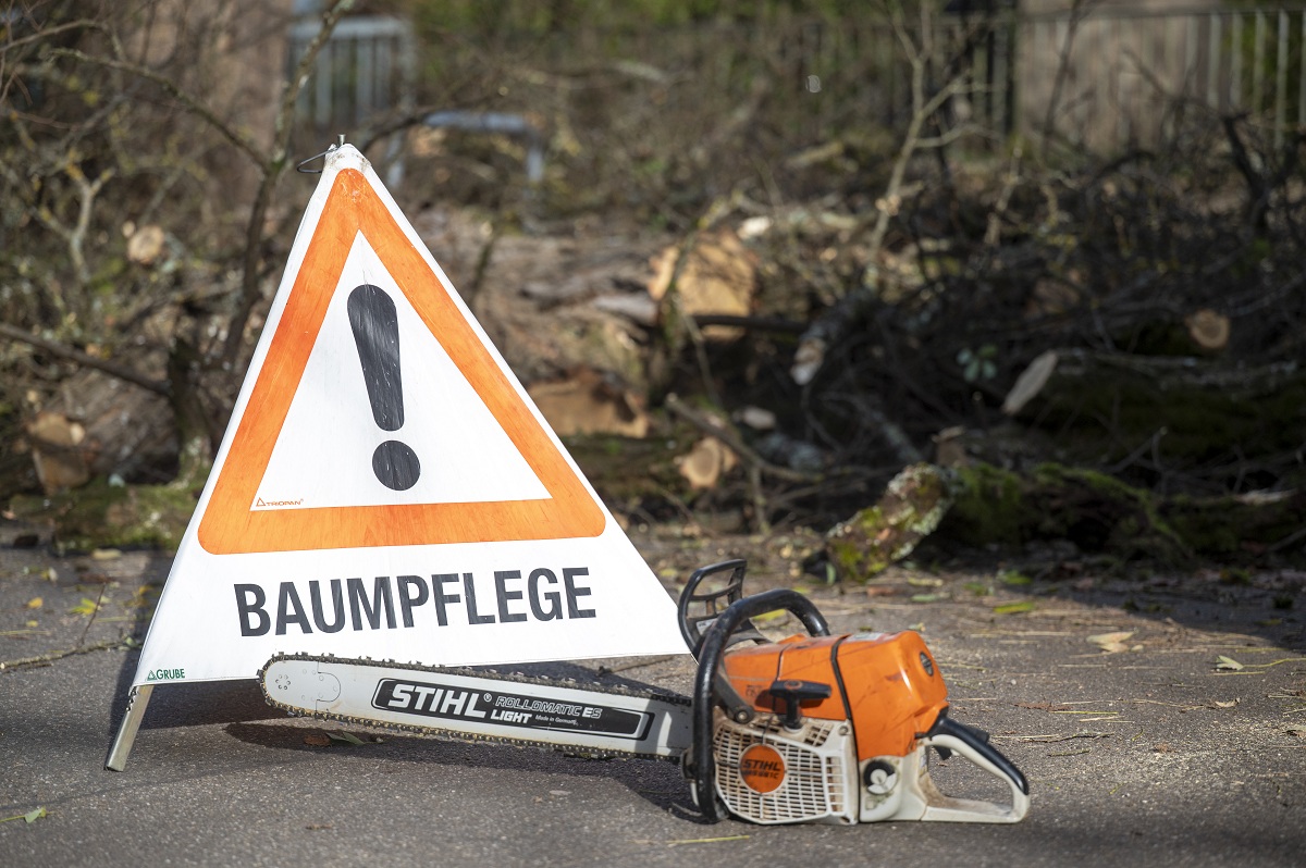 Ein Warndreieck "Baumpflege" mit einer Motorsäge davor.