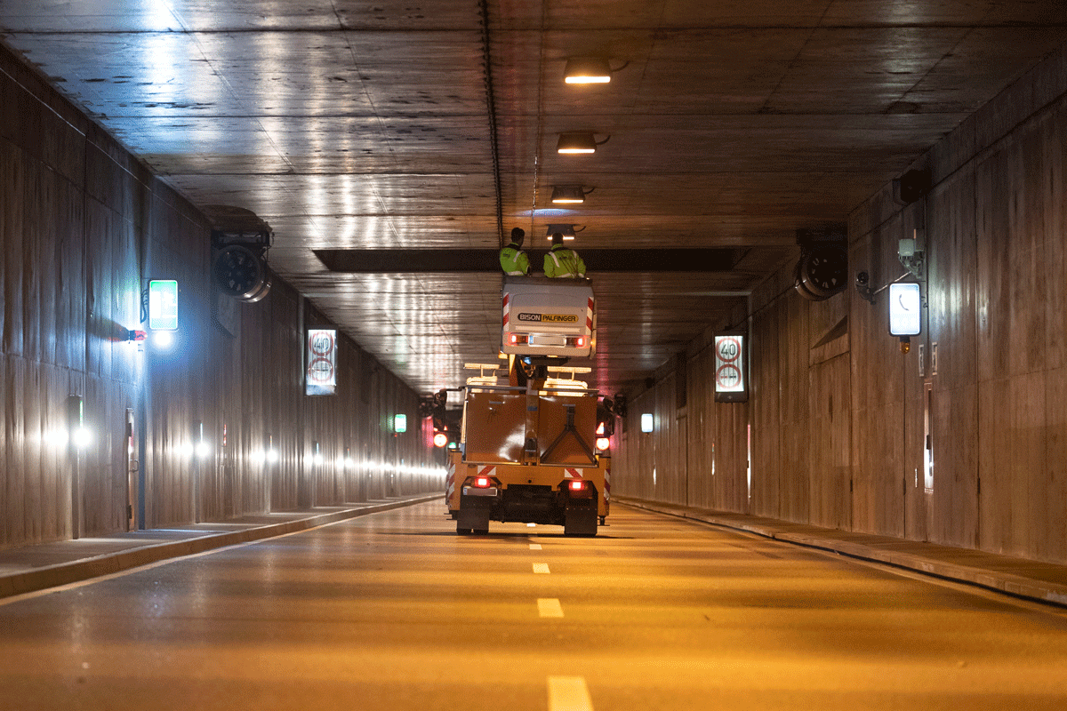 Zwei Personen stehen auf einem Arbeitsauto und schauen sich einen Tunnel an