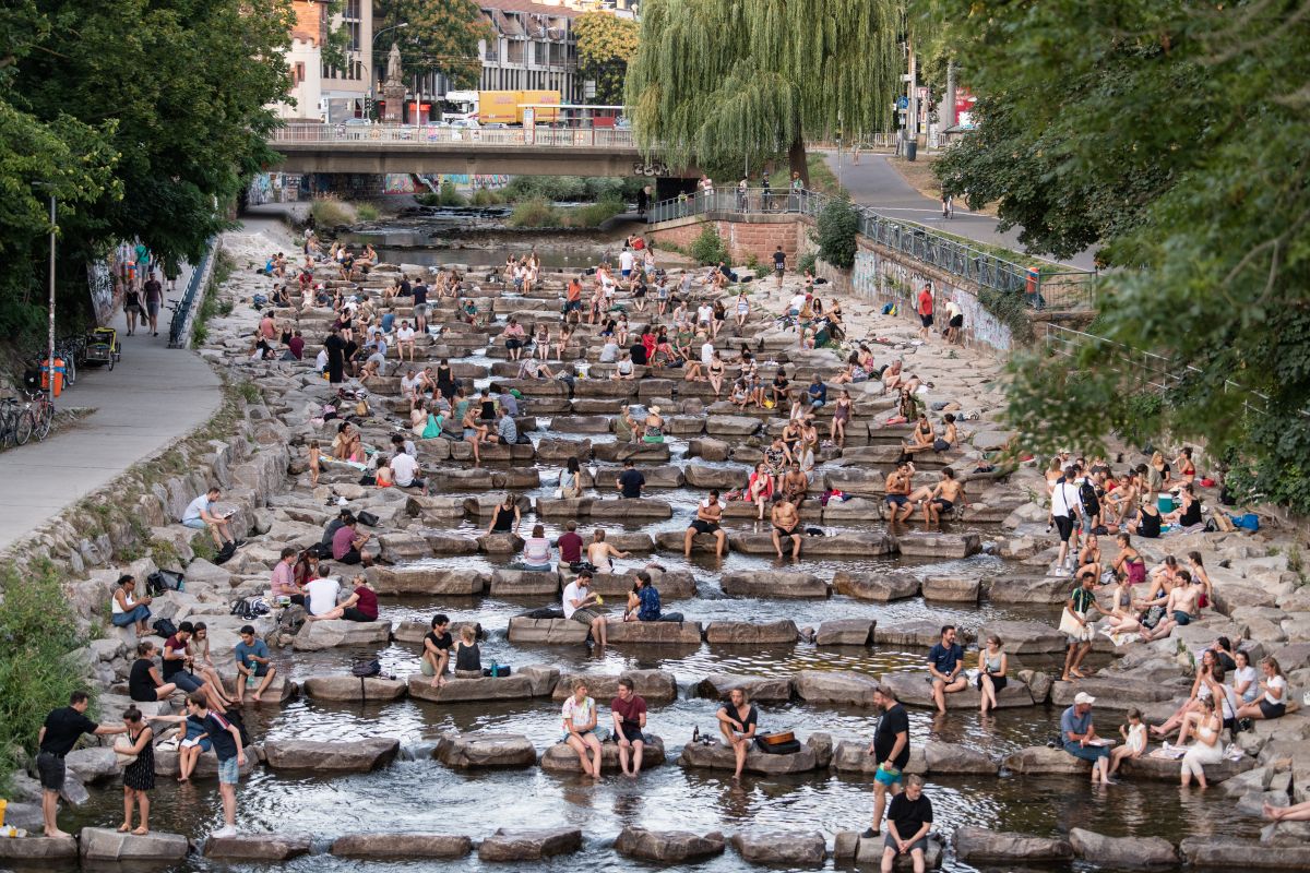 Viele Menschen sitzen an den Fischtreppen an der Dreisam