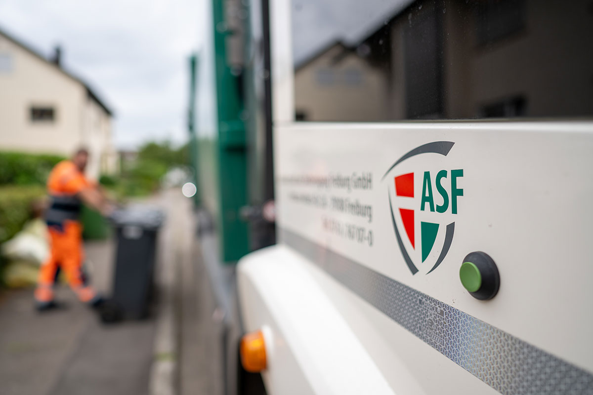 Fahrzeug der ASF, im Hintergrund Mitarbeiter mit Tonne