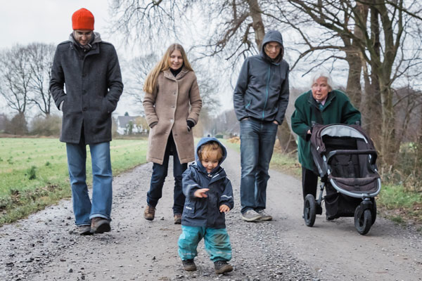 Fünfköpfige Familie beim Spaziergang mit Kinderwagen