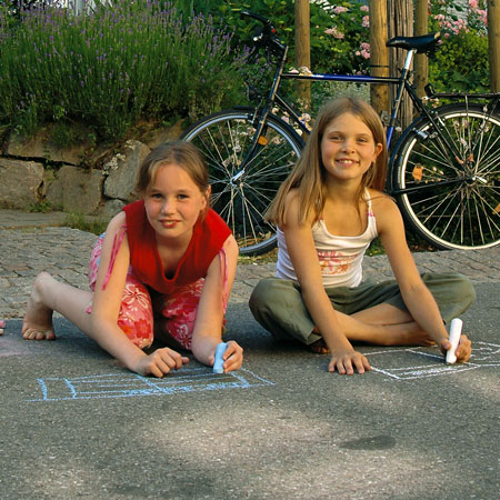 Zwei Mädchen malen mit Kreide auf der Straße