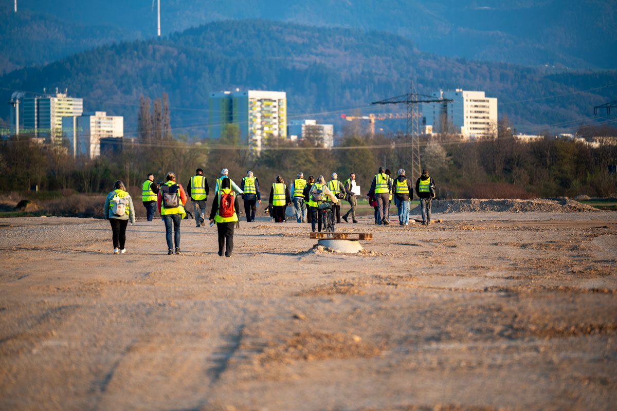 Viele Menschen laufen in einer Warnweste über eine große Baufläche