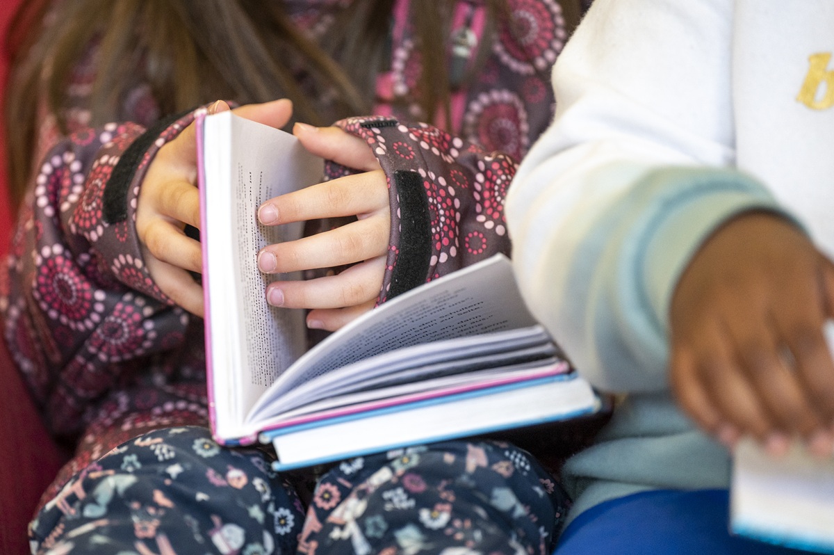 Zwei Kinder blättern durch ein Buch.