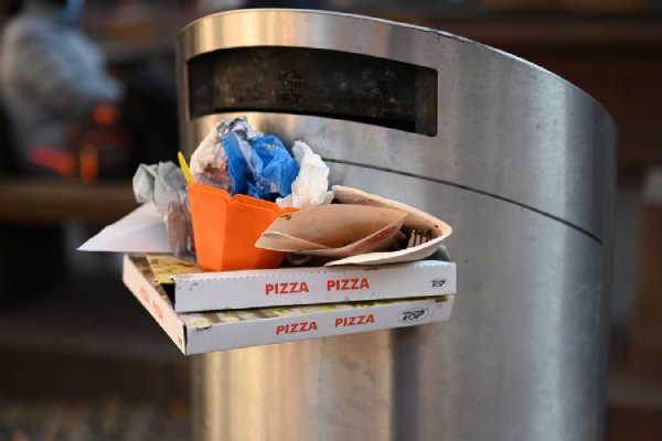 Überfüllter Mülleimer mit Pizzakartons und Eisbechern