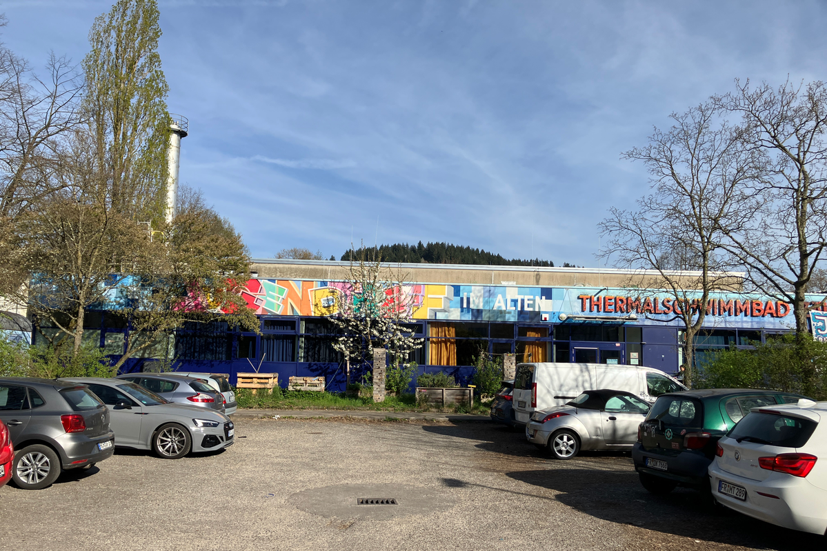 Parkplatz mit abgestellten Autos und Flachbau im Hintergrund