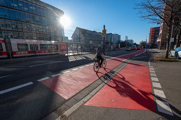 Radfahrerin auf rot markiertem Radweg, Straßenbahn im Hintergrund