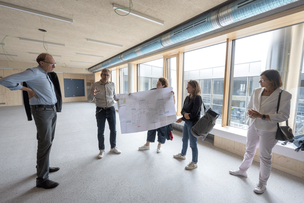 Mehrere Menschen stehen auf einer Baustelle und halten einen Plan