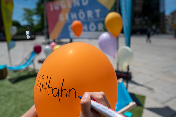 ein Luftballon wird mit einem Stift beschriftet "Dirtbahn" als Wunsch von Jugendlichen