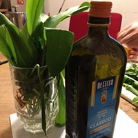 Grüne Pflanze in einem Wasserglas und grüne Glasflasche auf einem Tisch stehend