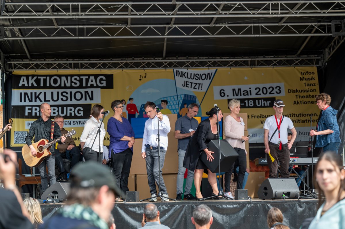 Eine Bünhe mit Musiker*innen und Organisator*innen. Im Hintergrund ein Banner zum Aktionstag.