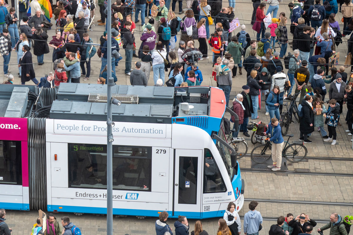 Straßenbahn vor dem Stadttheater, viele Menschen im Rahmen einer Versammlung