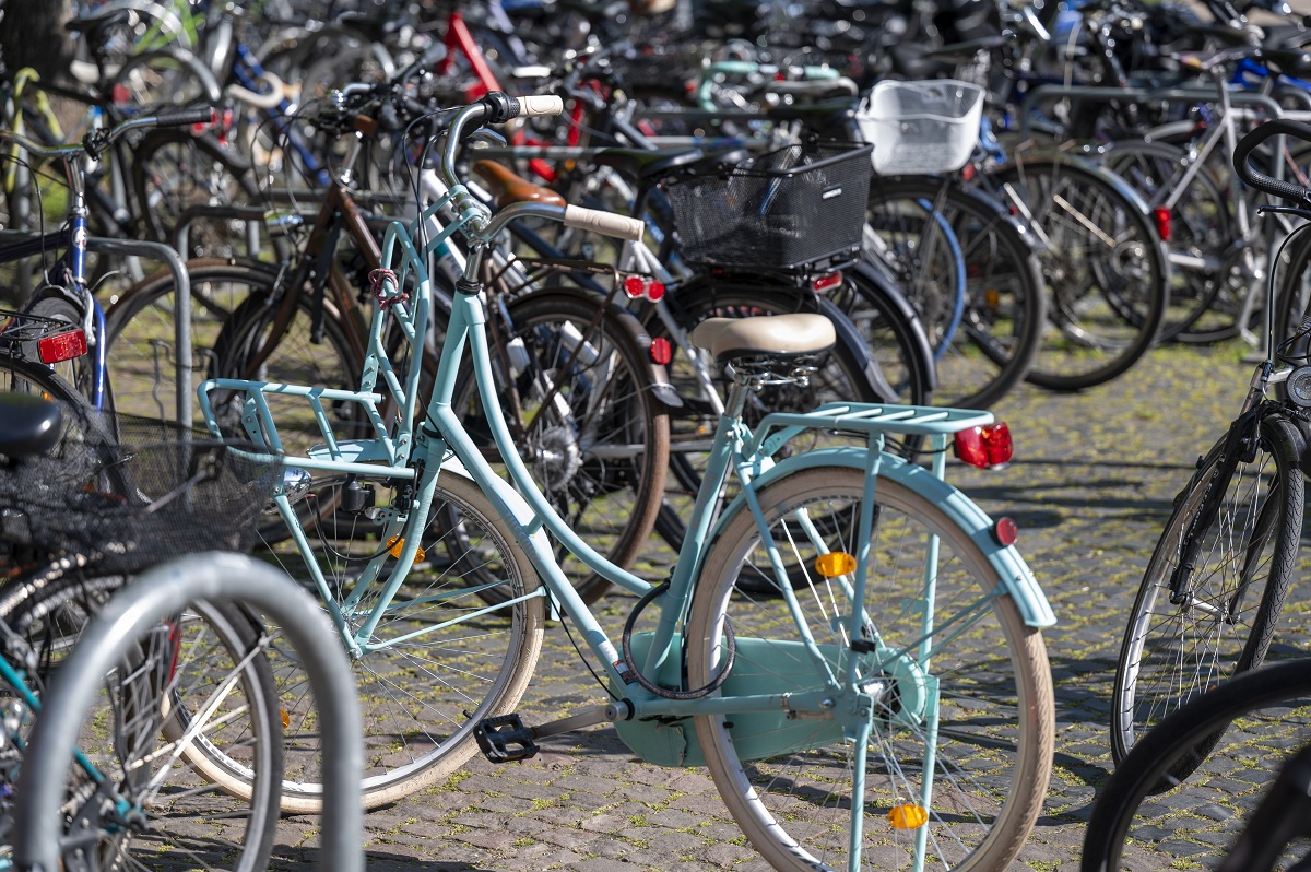Viele abgestellte Fahrräder, im Mittelpunkt ein hellblaues Hollandrad
