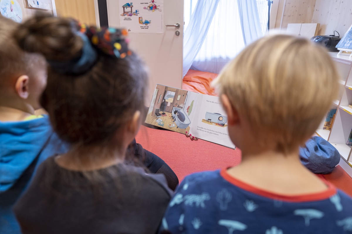 Drei Kinder schauen sich ein Buch an.