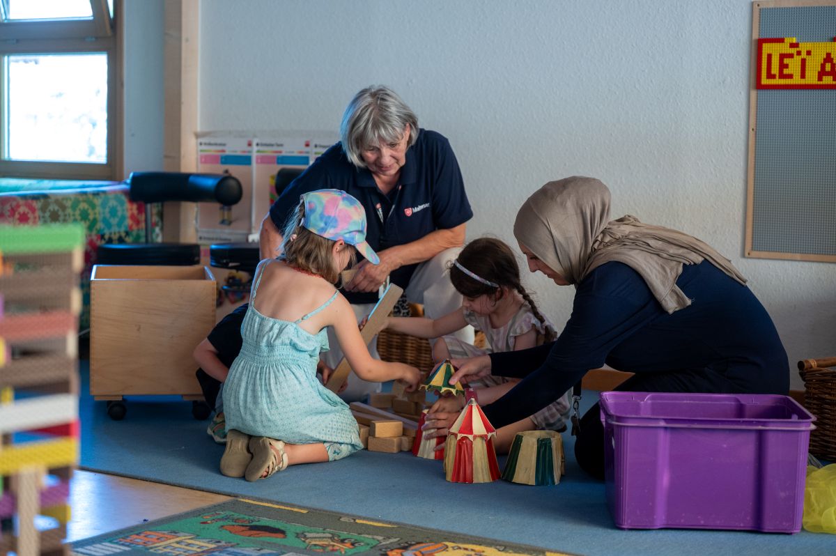 Zwei Mitarbeiterinnen der Malteser spielen mit zwei Kita-Kindern.
