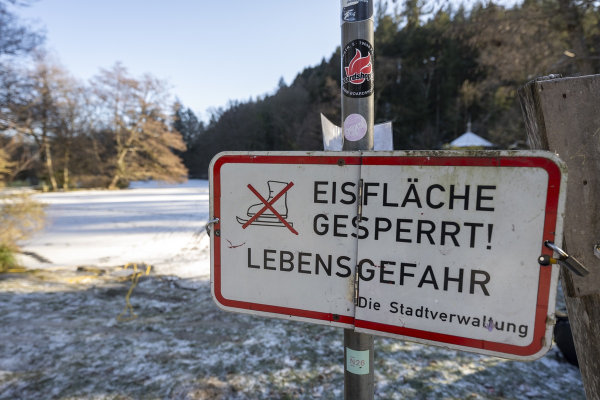 Ein Schild vor einem zugefrorenen See mit der Aufschrift: Eisfläche gesperrt! Lebensgefahr. Die Stadtverwaltung.