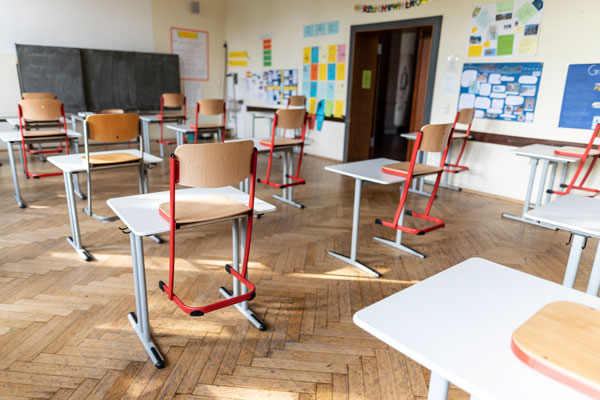 Klassenzimmer mit Stühlen, Tischen, einer Tafel