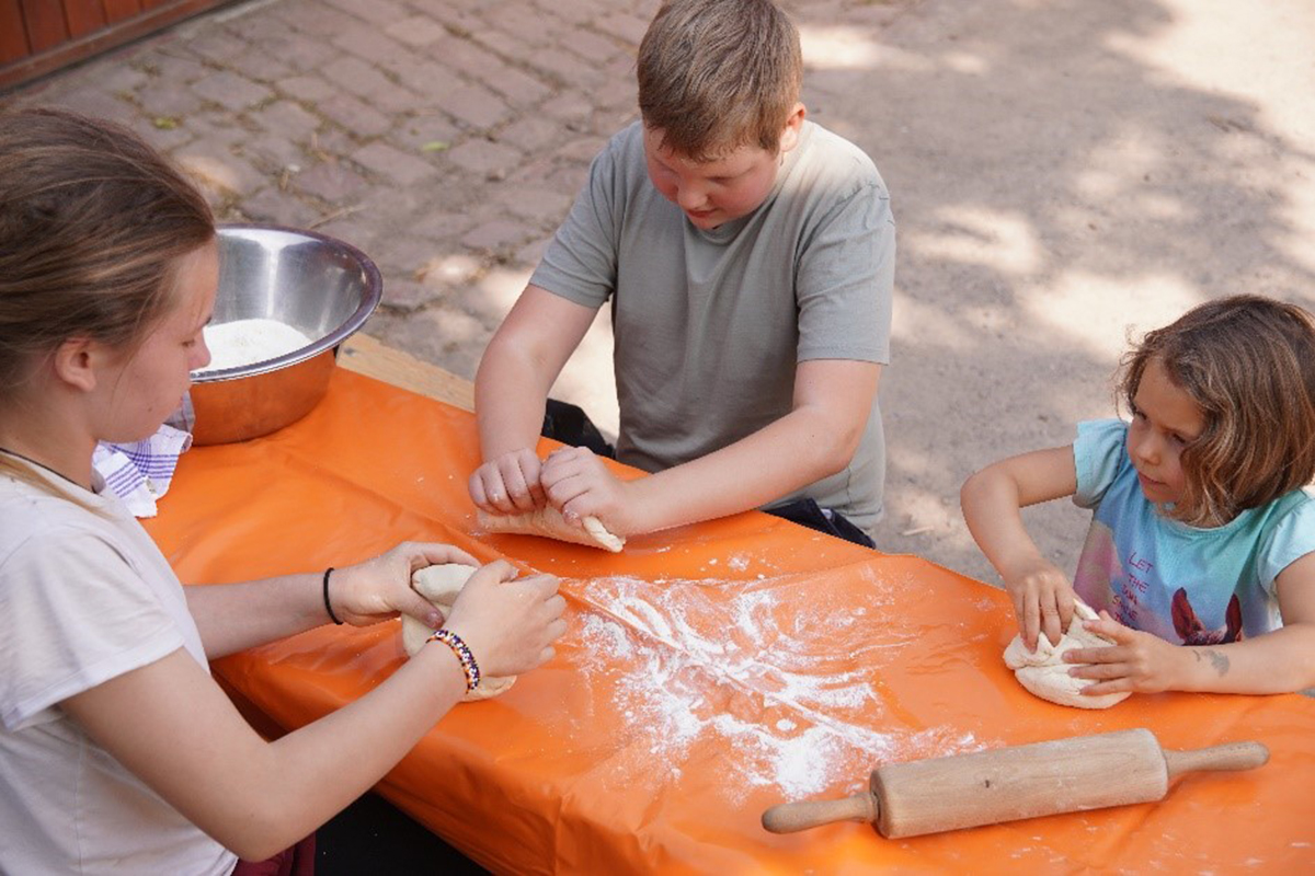 Kinder verarbeiten Mehl zu einem Brotteig