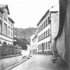 Gasse mit Häuserfronten an jeder Seite, Blick auf die Alte Adelhauser Schule in Freiburg