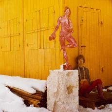 Priska von Martin mit ihrer Skulptur 'Rote Mädchen' vor einem gelbem Holzschuppen im Schnee
