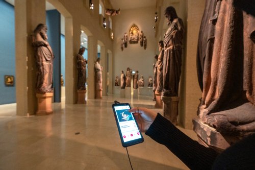 Person mit Smartphone, auf dem die Augustiner App geöffnet ist, in der Skulpturenhalle