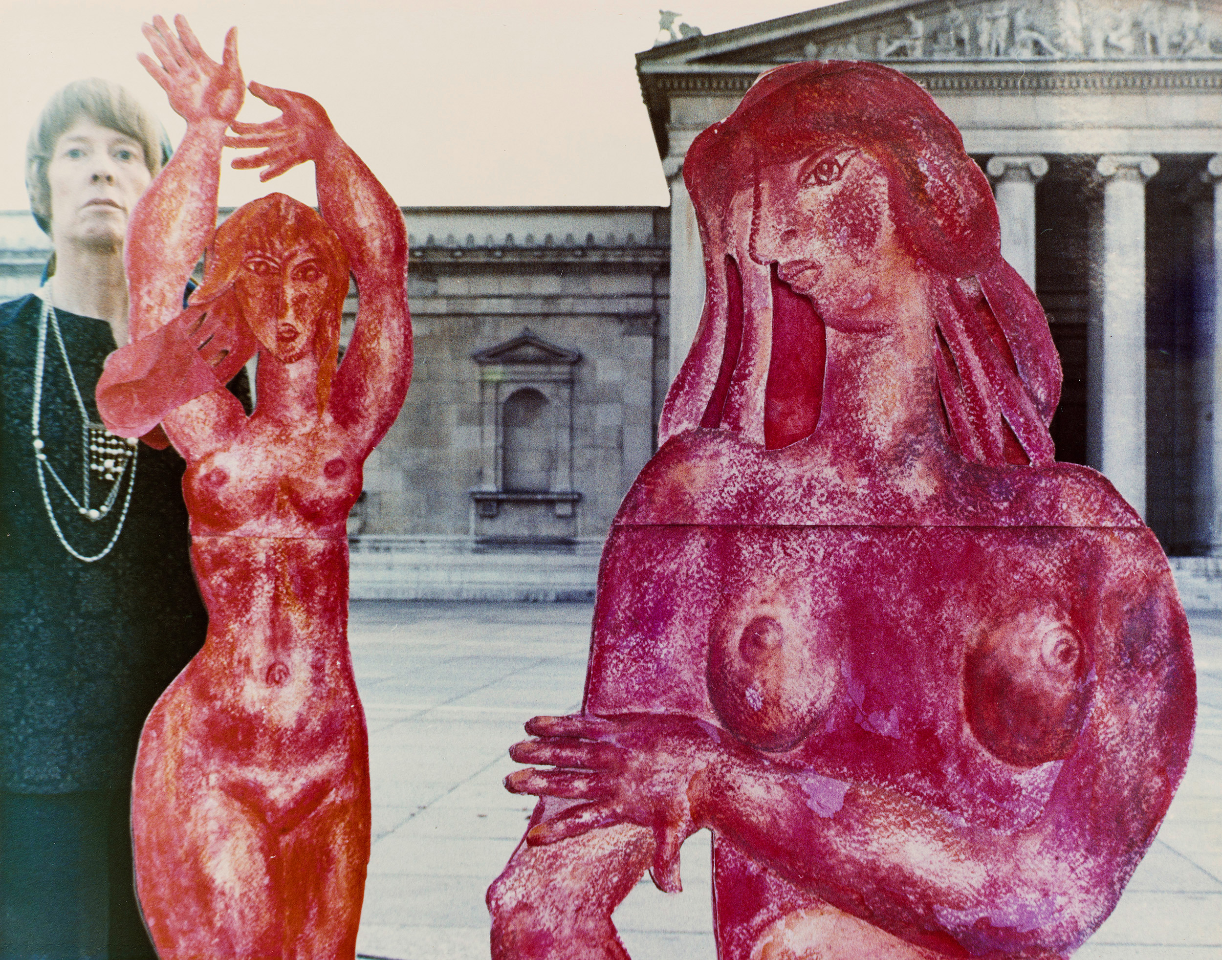 Foto von Priska von Martin mit zwei von ihr geschaffenen lebensgroßen, rot bemalten Frauenfiguren aus Pappe