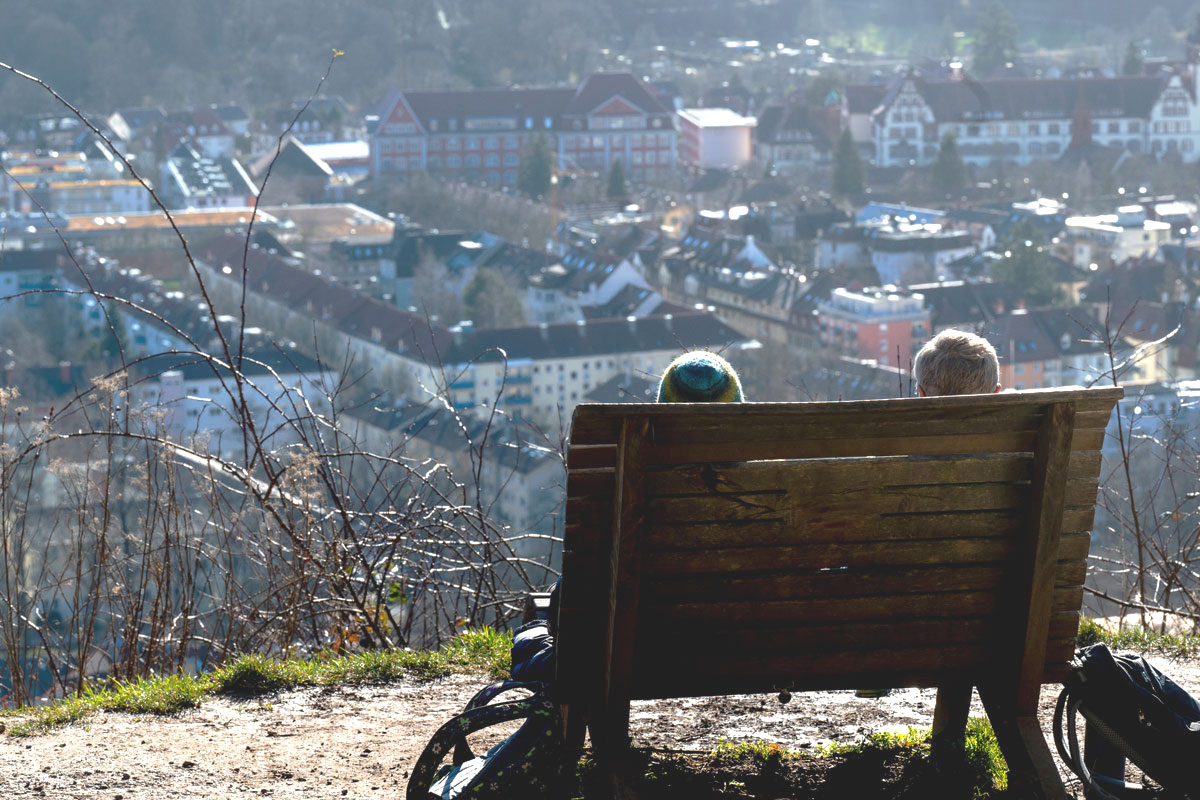 Zwei Menschen sitzen auf einer Bank und schauen auf Freiburgs Panorama.