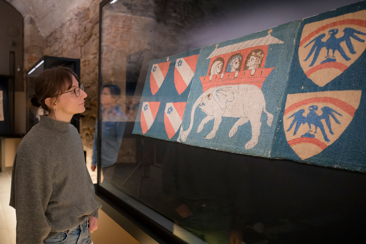 Frau steht vor Wandteppich schaut sich diesen an