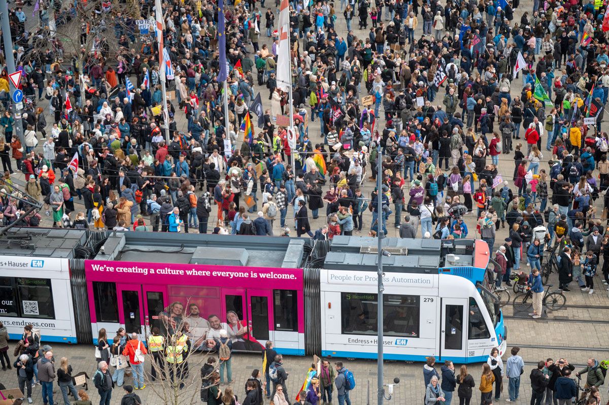 Demonstration mit vielen Menschen, eine Straßenbahn kreuzt den Weg