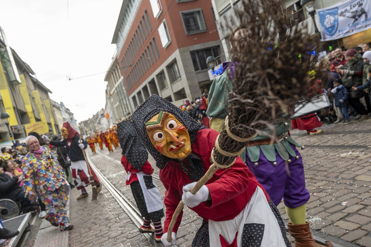 Eine Person als Hexe im Häs verkleidet, hält ihren Besen in die Kamera.